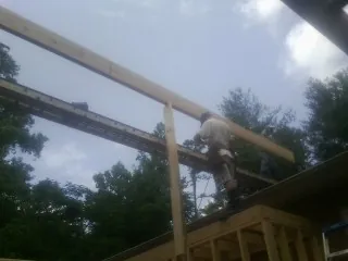 Carpenter setting a ridge beam over a new addition frame — Ice Dam Removal by Roofing Brothers in Evans