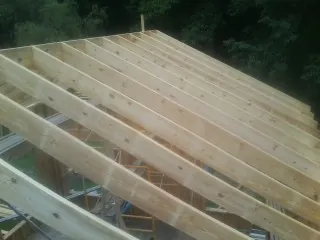 New roof rafters set over an addition before sheathing in Evans