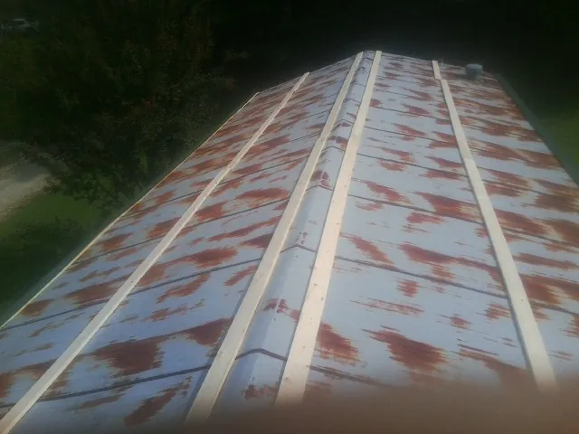 Rusted metal roof panels with new wood purlins before replacement — Storm Damage Roof Repair in Evans by Roofing Brothers